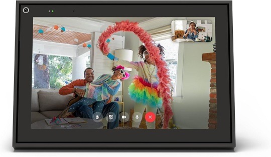 A black smart video calling device with a 10" touch screen display, sitting on a table in a living room setting.