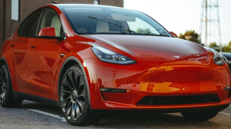 red Tesla Model 3 electric car parked in a parking lot