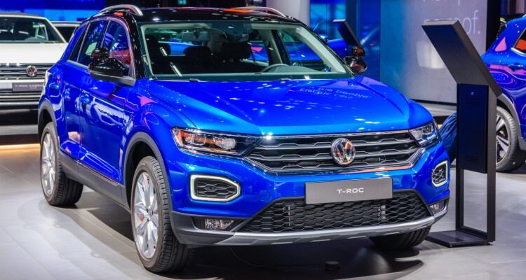 A shiny new 2022 blue Volkswagen T-Roc displayed in a well-lit showroom